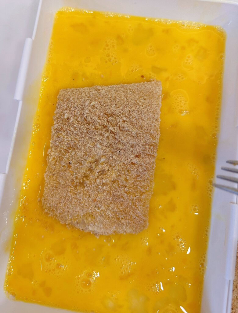 Dredging bread coated fish in egg batter again.