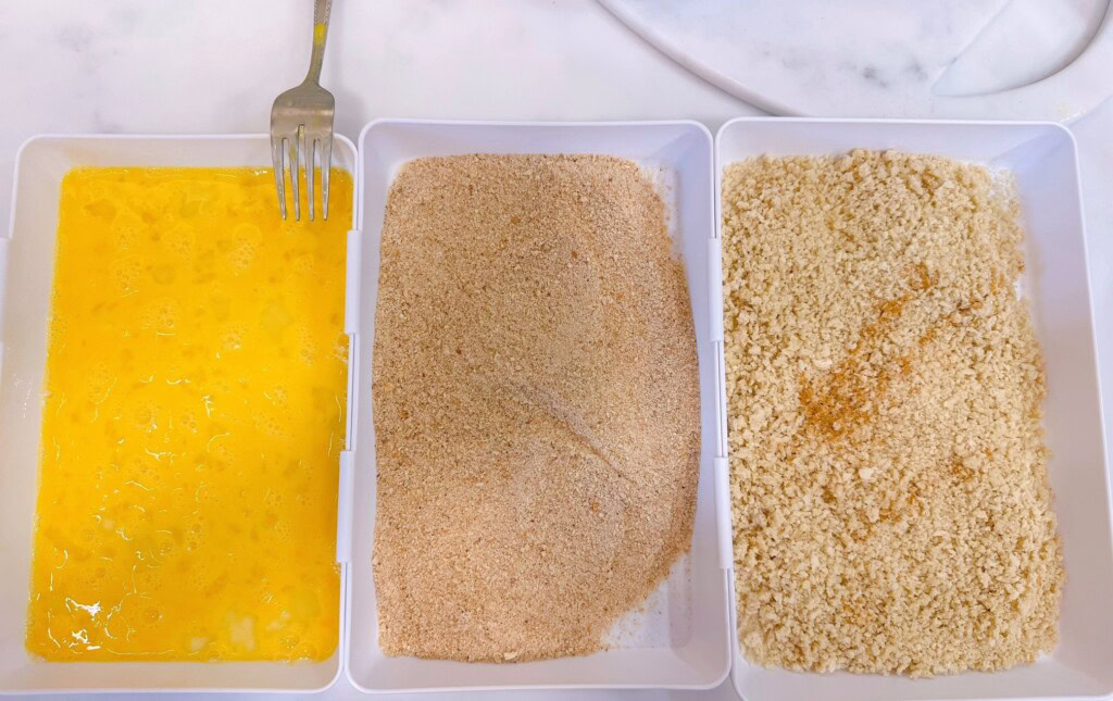 Eggs and bread crumbs in dredging trays for fish.