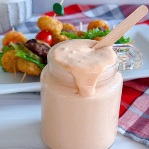 Secret Sauce in a jar dripping over the edge with burger bites in the background.