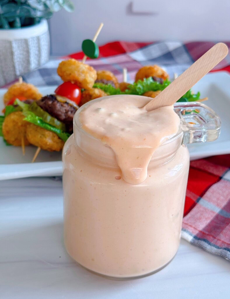 Secret Sauce in a jar dripping over the edge with burger bites in the background.