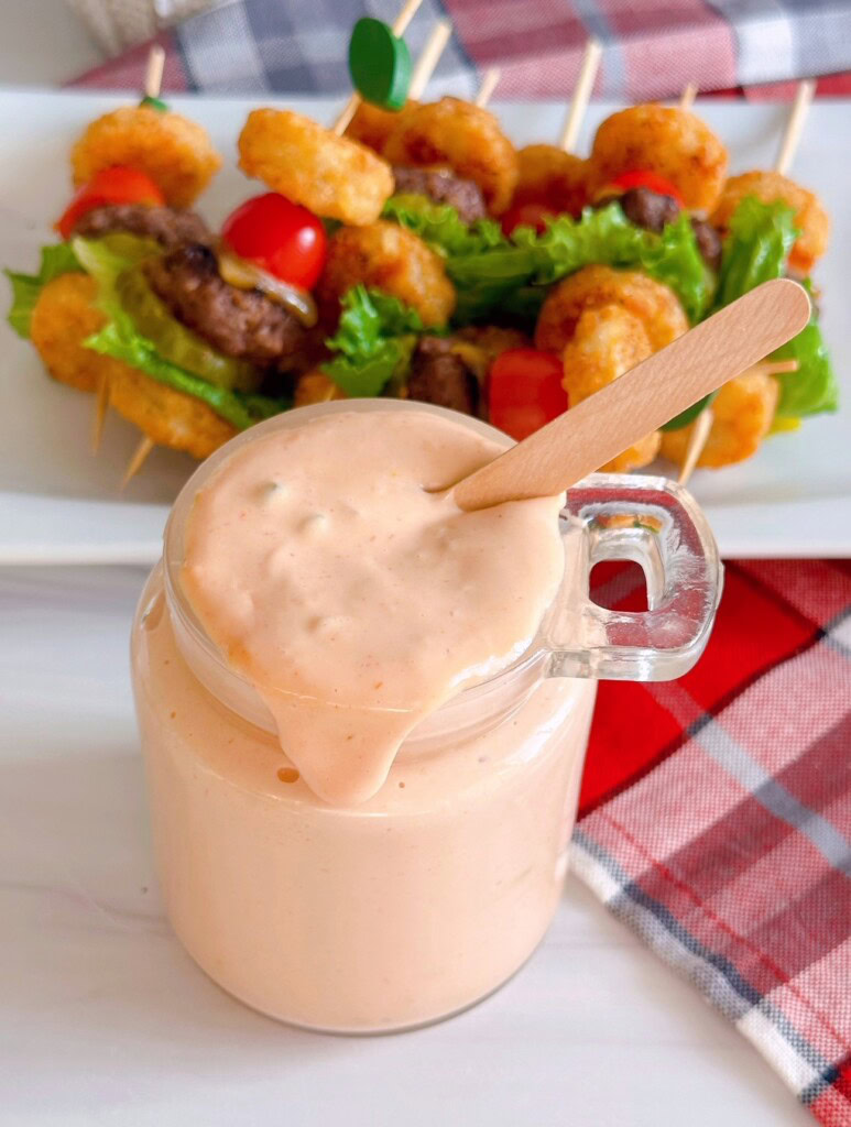 Overhead shot of secret sauce in a jar with a wooden serving spoon.
