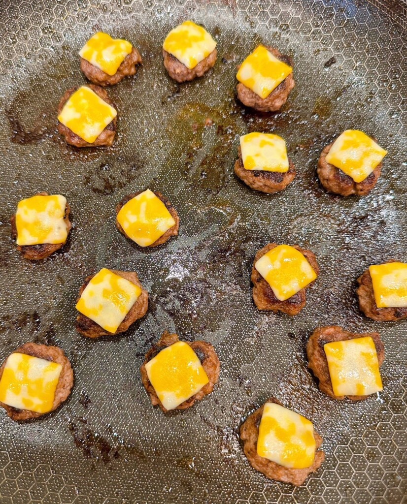 Adding cheese slices to mini hamburger patties. 