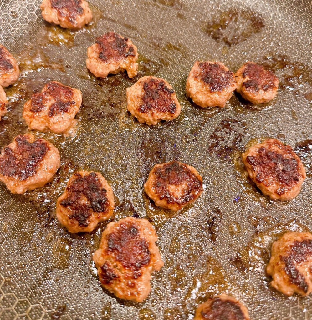 Cooking mini ground beef patties.