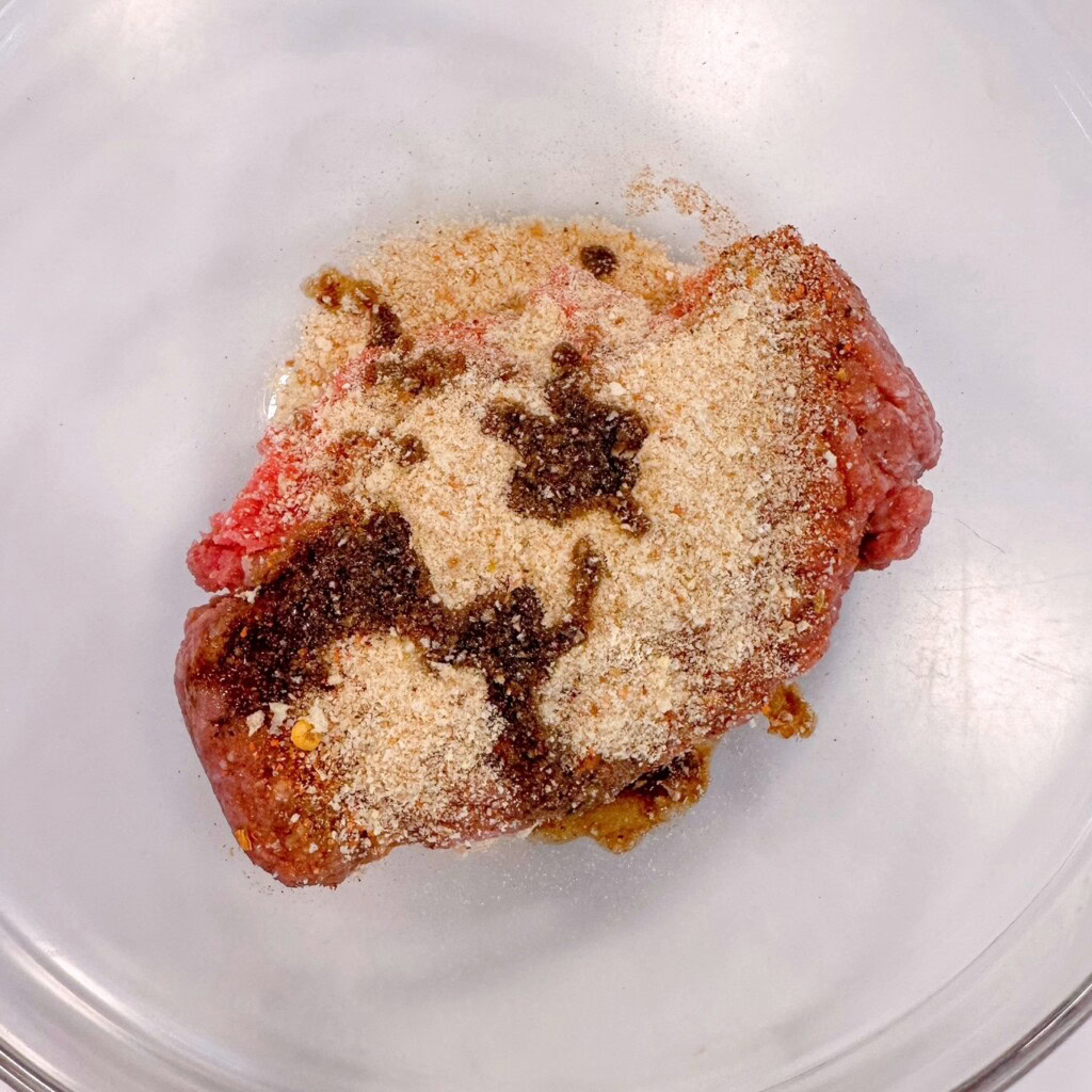 Adding ingredients to ground beef in a medium bowl.