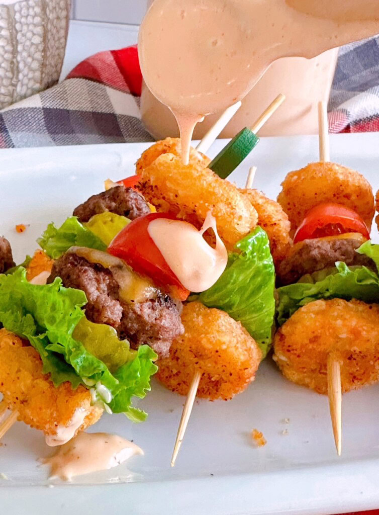 Applying secret sauce to mini cheeseburger bites.