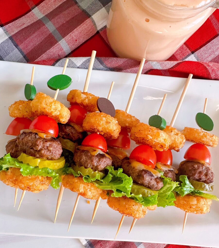 Mini cheeseburger bites on football skewers for a Superbowl party and arranged on a platter.