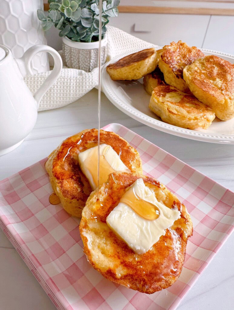 Biscuit French Toast on a plate with maple syrup pouring over the biscuit.