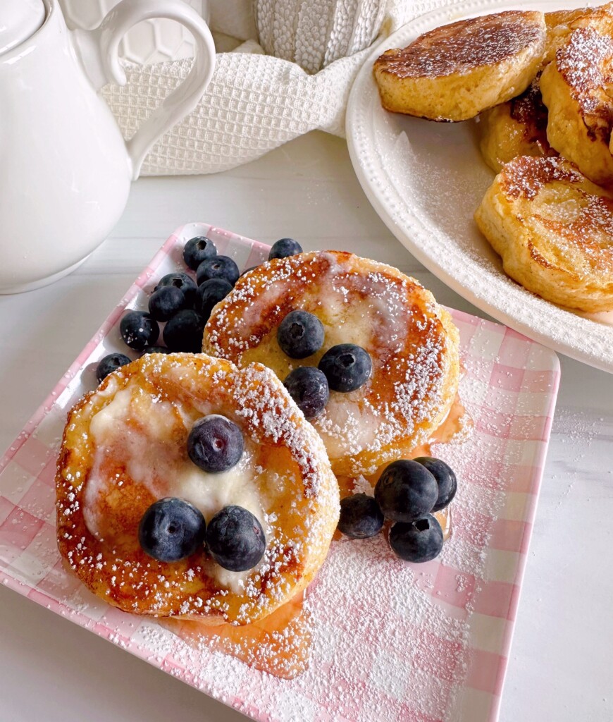 Biscuit French Toast with powdered sugar, blueberries, and maple syrup.
