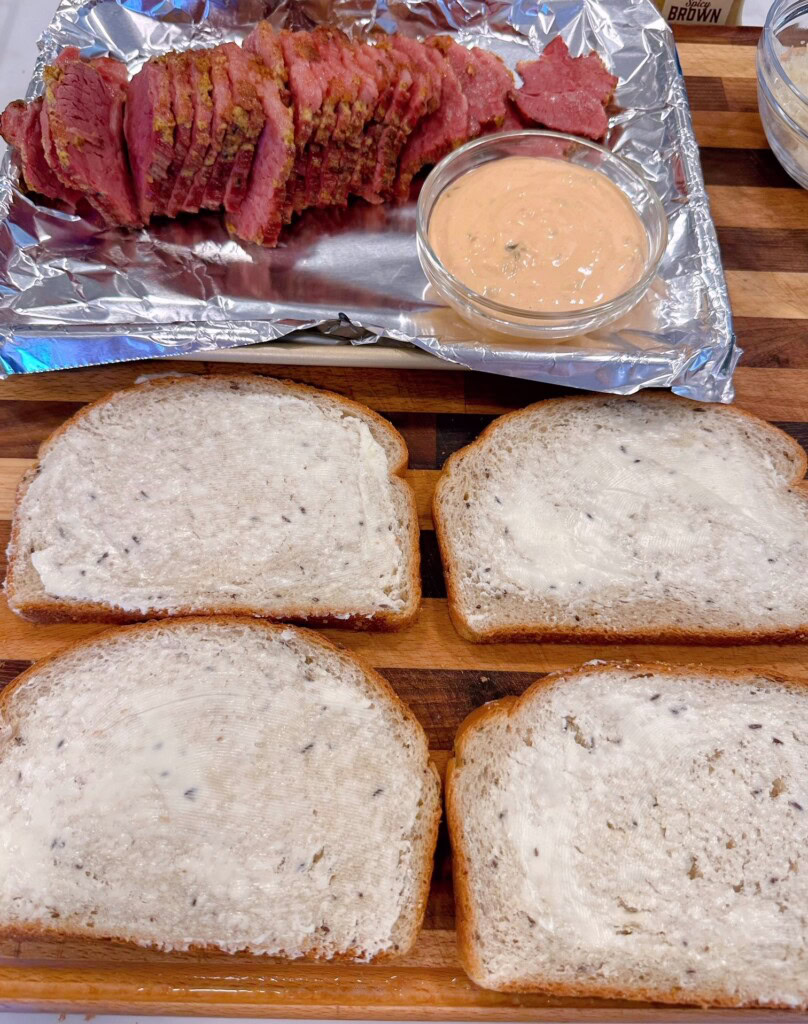 Two slices of bread with butter spread on the outside of each slice.