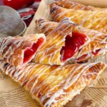 Cherry turnovers broken open and piled high on printed parchment paper.