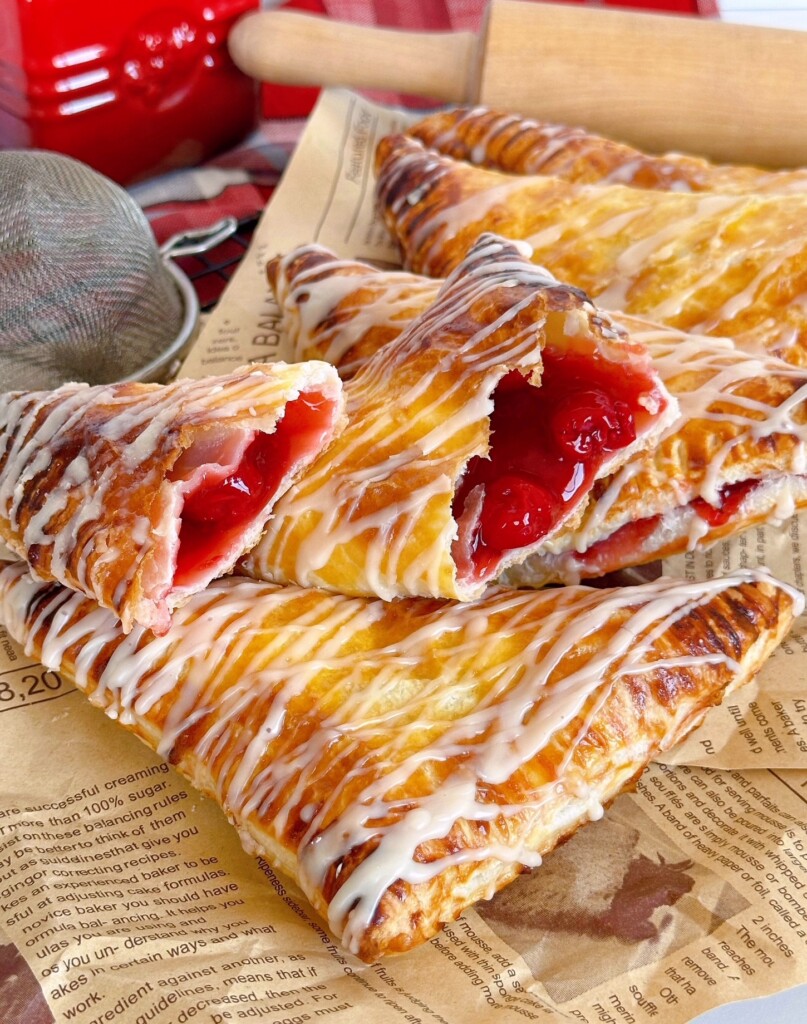 Cherry turnovers broken open and piled high on printed parchment paper.