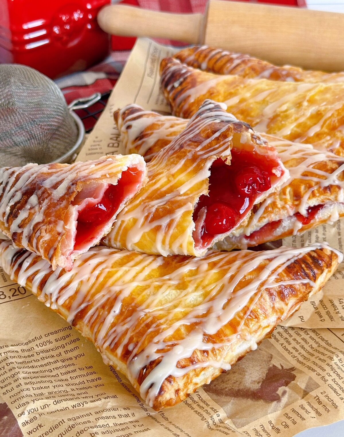 Cherry turnovers broken open and piled high on printed parchment paper.