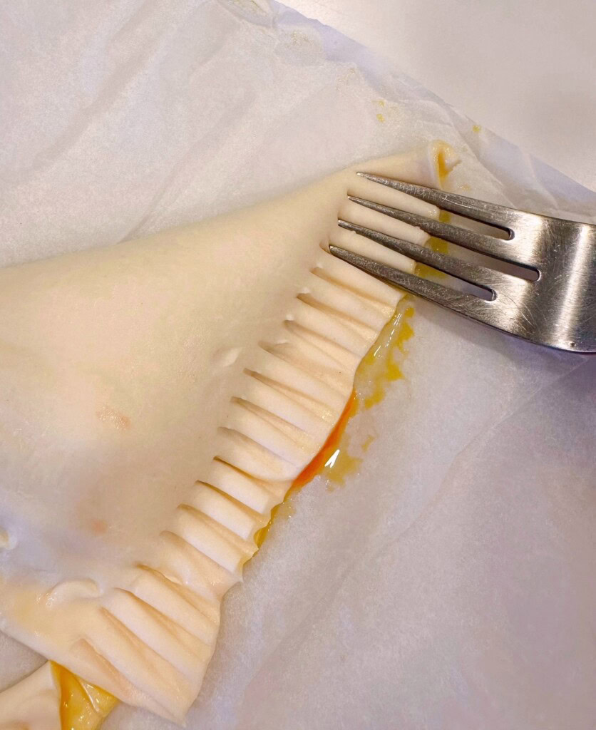 Cherry turnover folded over in half and using a fork to press edges together.