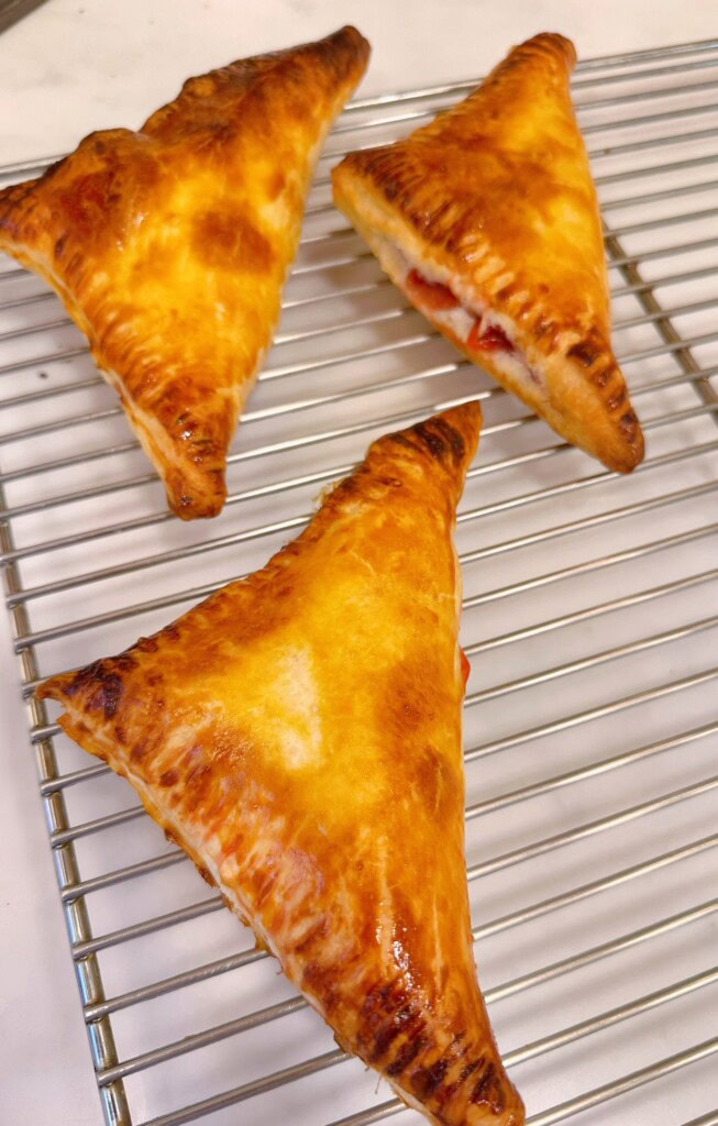 Baked cherry turnovers cooling on a baking rack.
