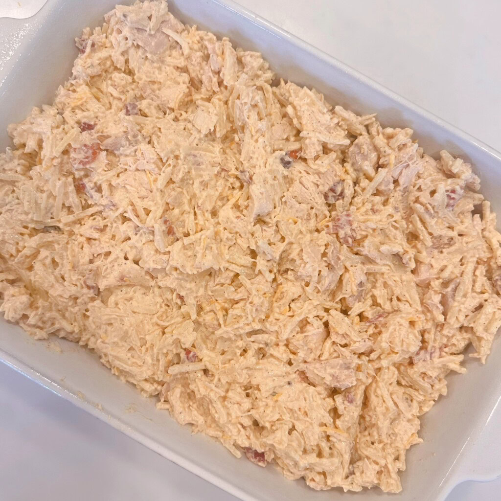 Pouring casserole ingredients into prepared casserole dish.