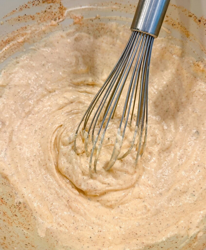 Cream sauce for casserole mixed in a bowl with a wire whisk.