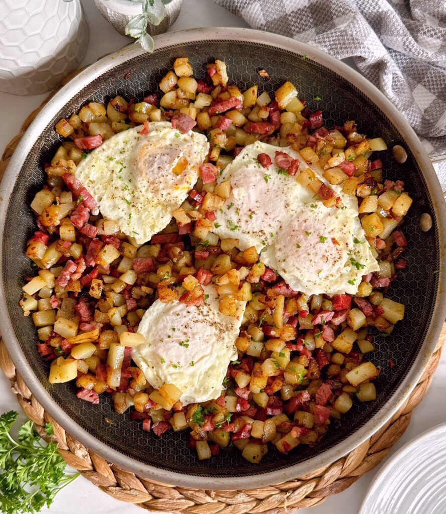 Eggs on top of corned beef hash in the skillet.