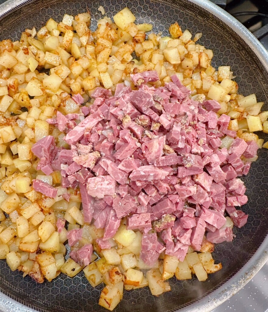 Adding corned beef to hash in the skillet.