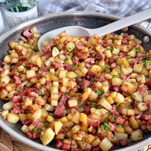 Skillet full of Corned Beef Hash with a serving spoon.