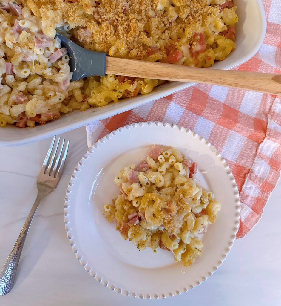 Ham and Noodle Casserole in a casserole dish with a serving on a dinner plate.