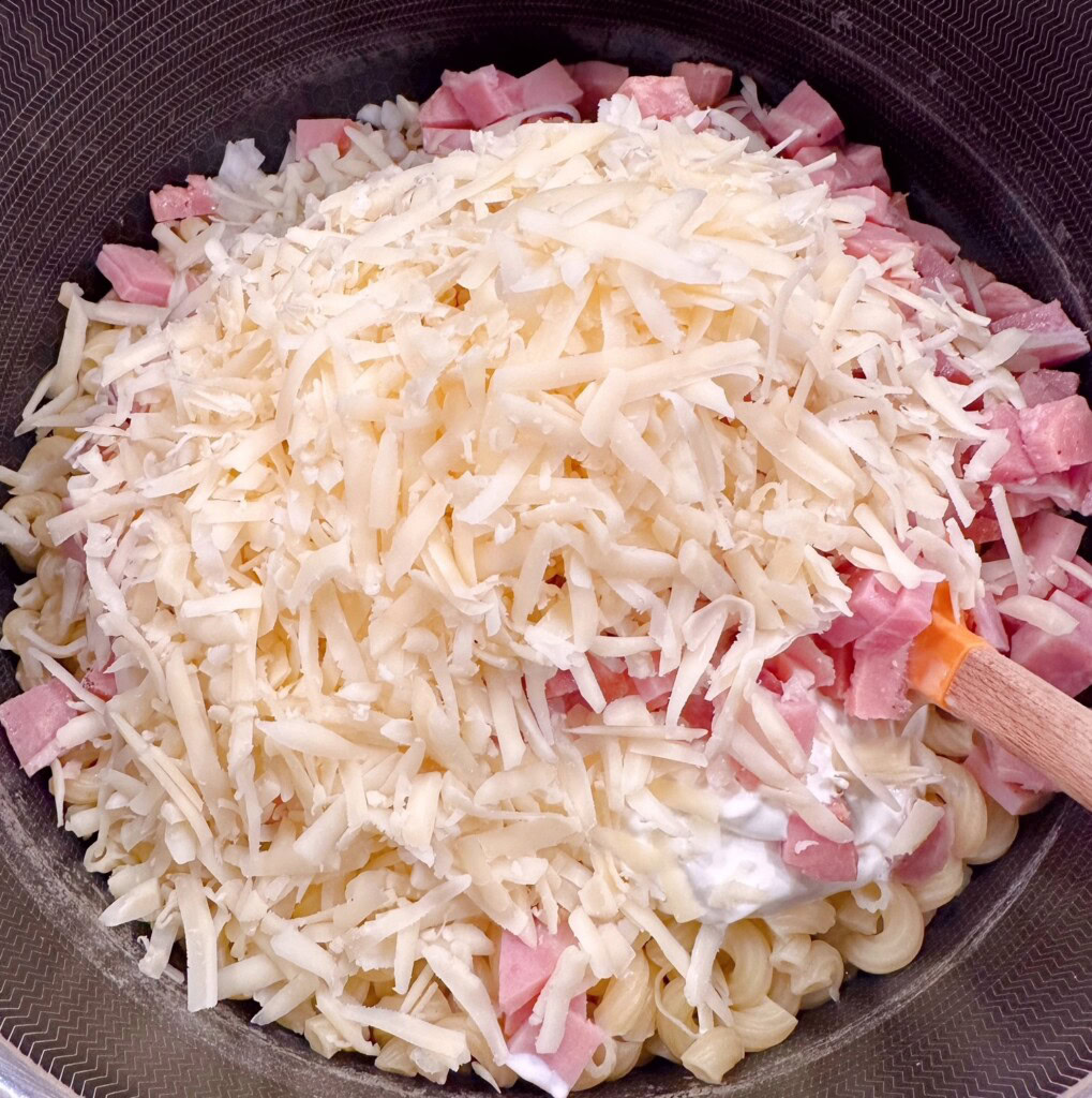 Adding Ham and Swiss Cheese to pasta mixture.