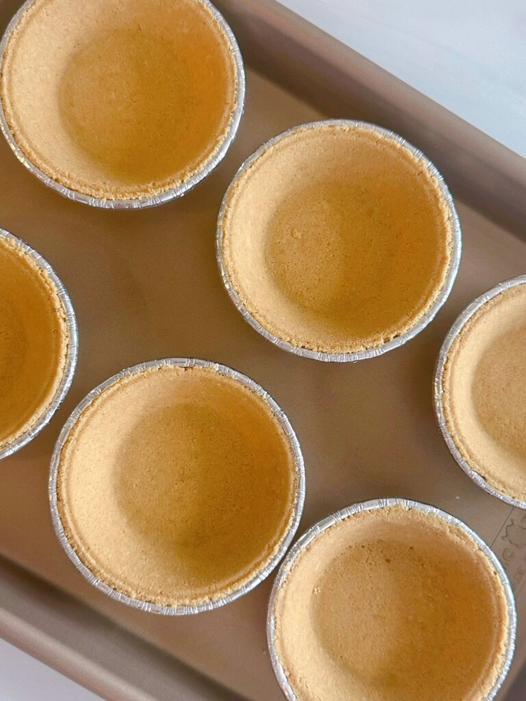 Baking sheet lined with mini-graham-cracker pie crusts.