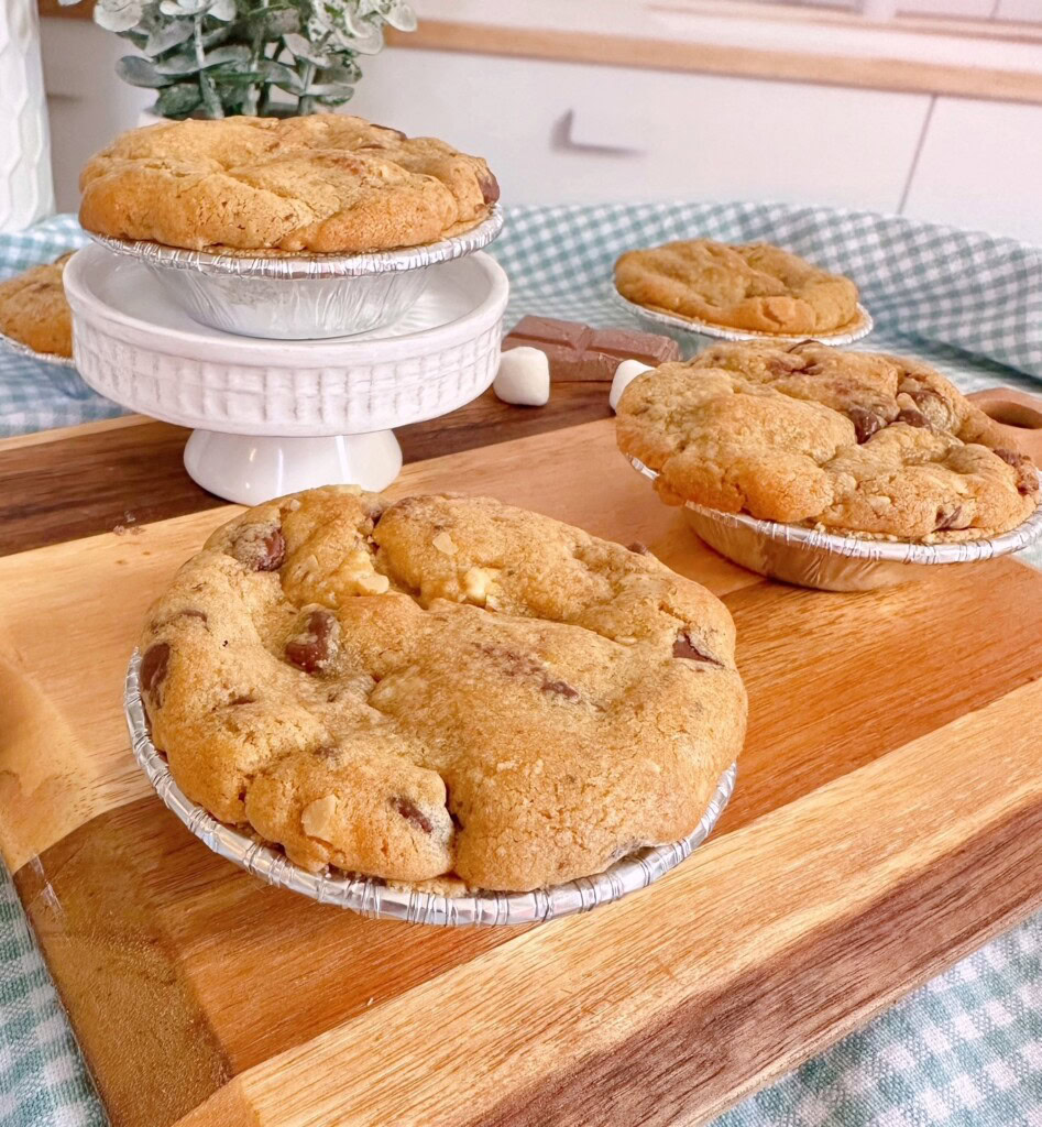 Mini Chocolate Chip S'mores Pies on a small cutting board cooling.