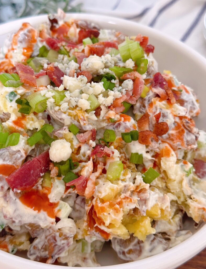 Close up photo of smashed potato salad with drizzle of buffalo sauce.