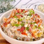 Close-up photo of Smashed potato salad with garnishes on top.