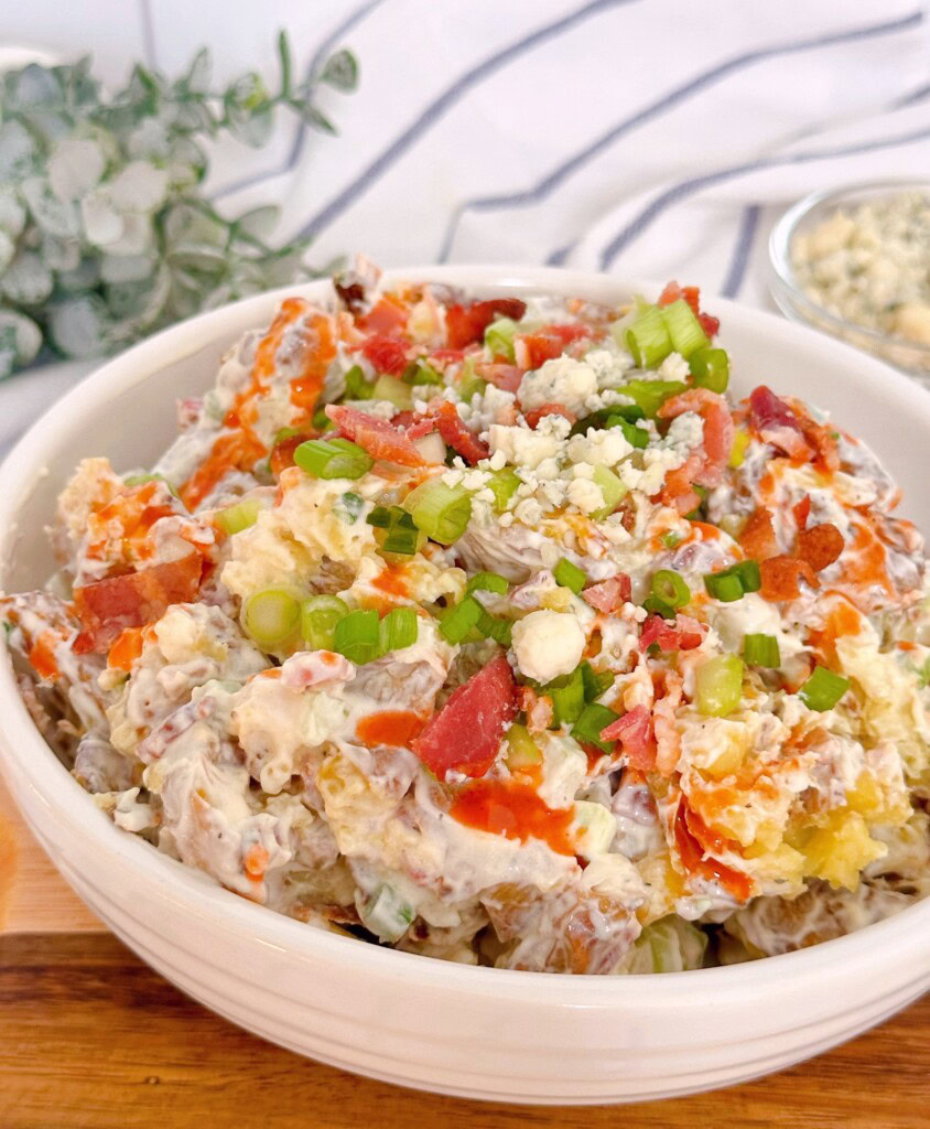 Close-up photo of Smashed potato salad with garnishes on top.