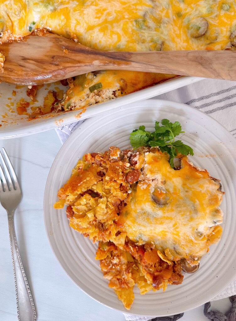 Easy Ground Beef Casserole in a casserole dish with a single serving on a dinner plate with a fork.
