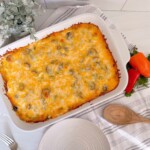 Taco Casserole out of the oven in the casserole dish with melted cheese, peppers and a wooden spoon.