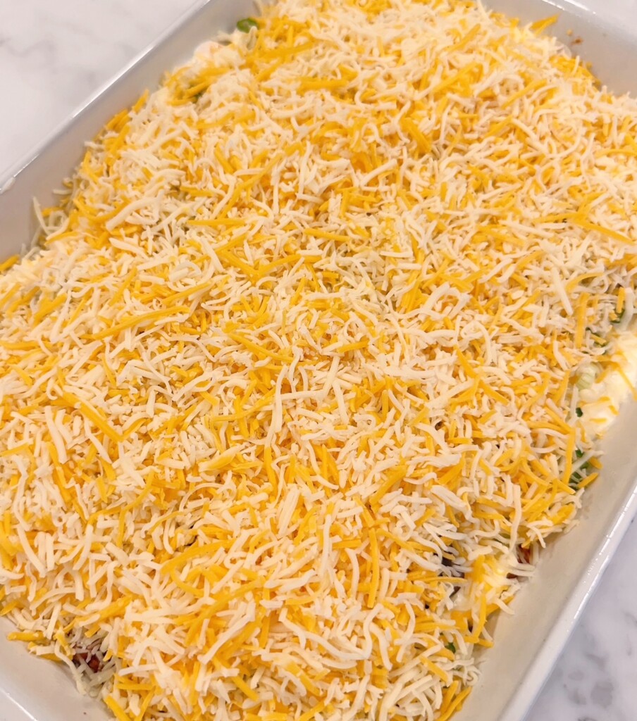 Adding grated cheese on top of the casserole.