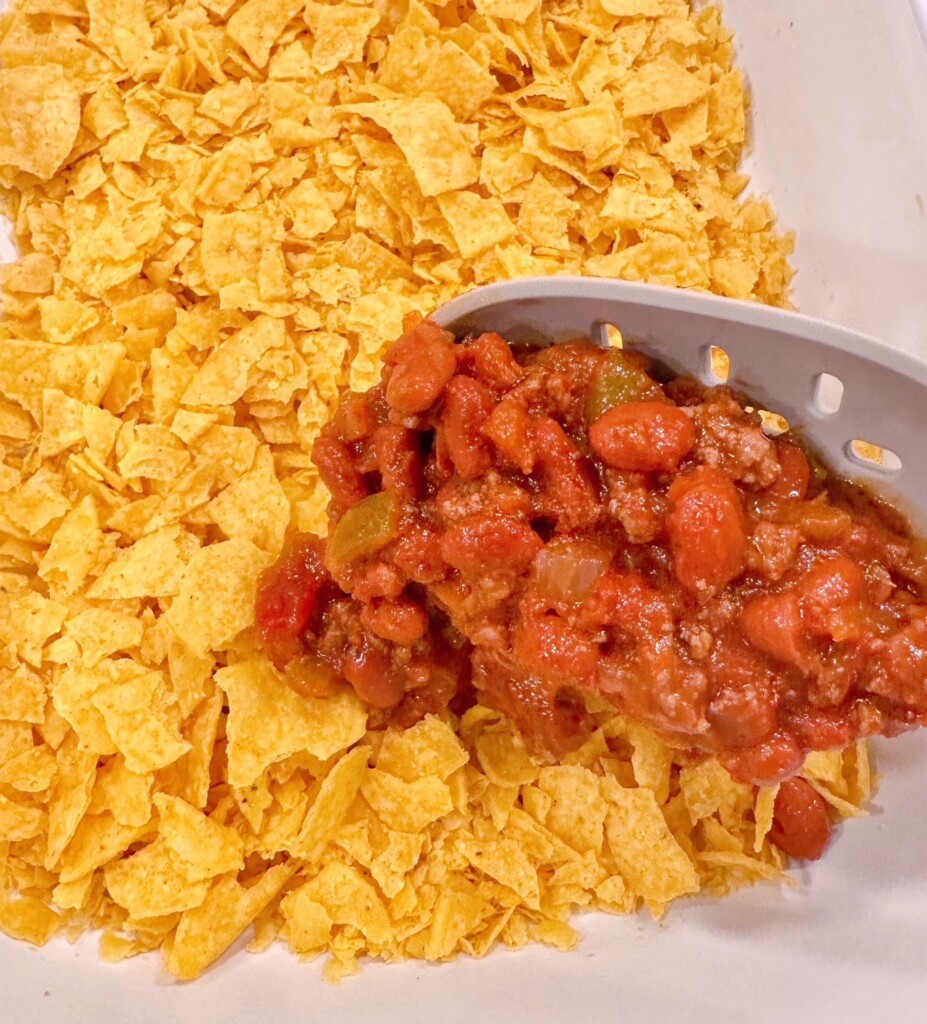 Layering beef mixture on top of crushed tortilla chips.