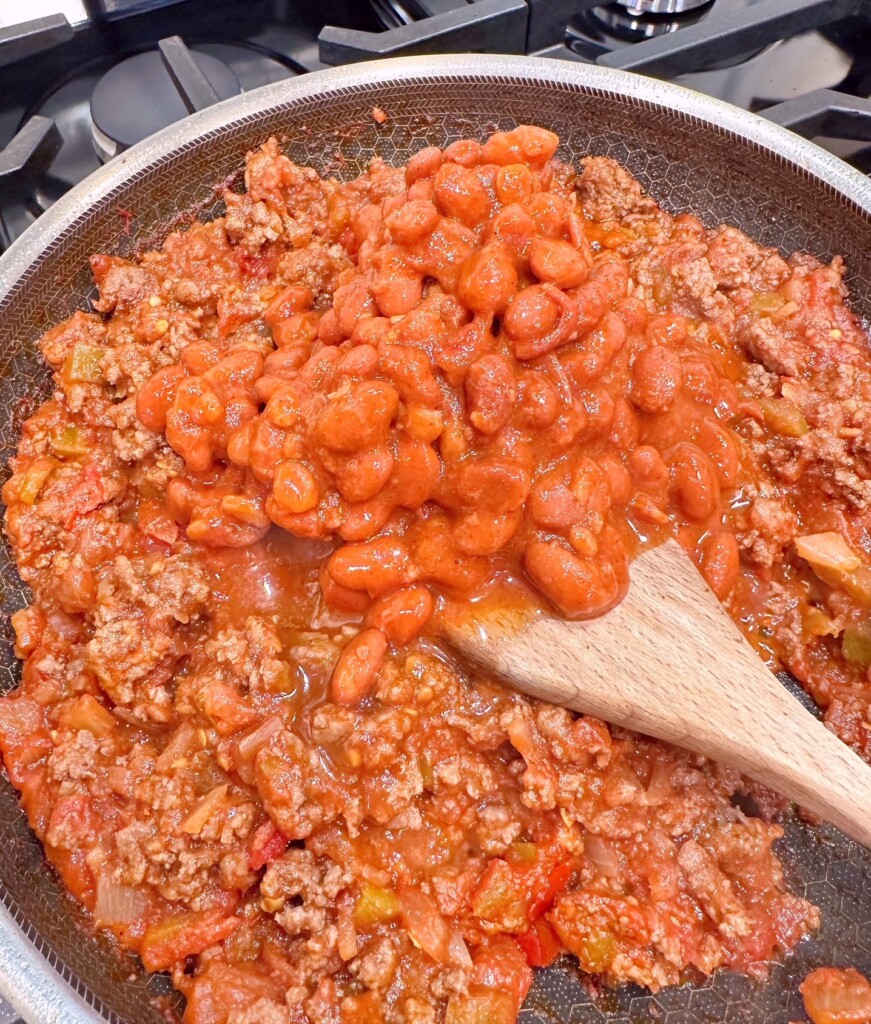 Adding chili beans to ground beef mixture.