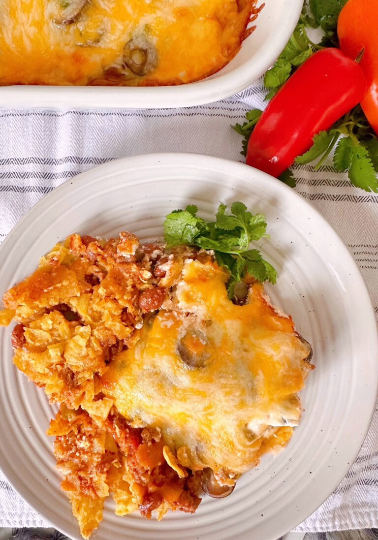 Taco Casserole on a serving plate with red bell pepper in the background.