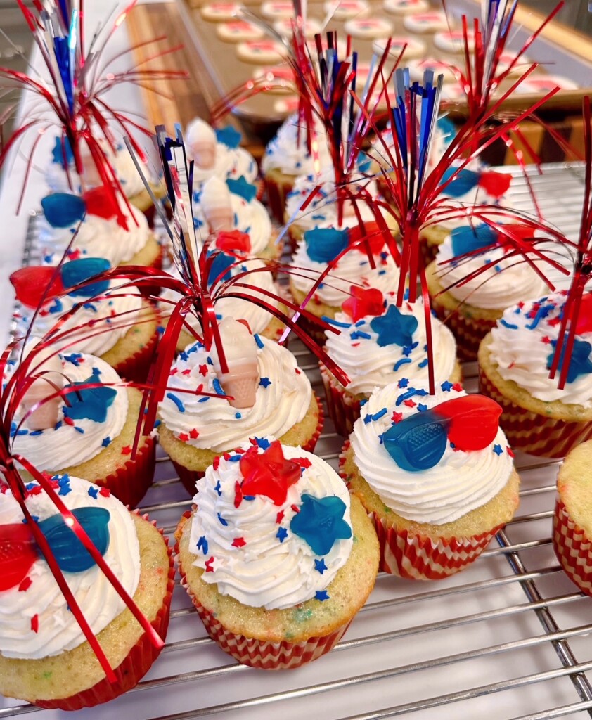 Cupcakes are decorated and on a rack.