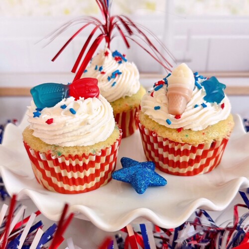 Three decorated cupcakes on a white cake stand.