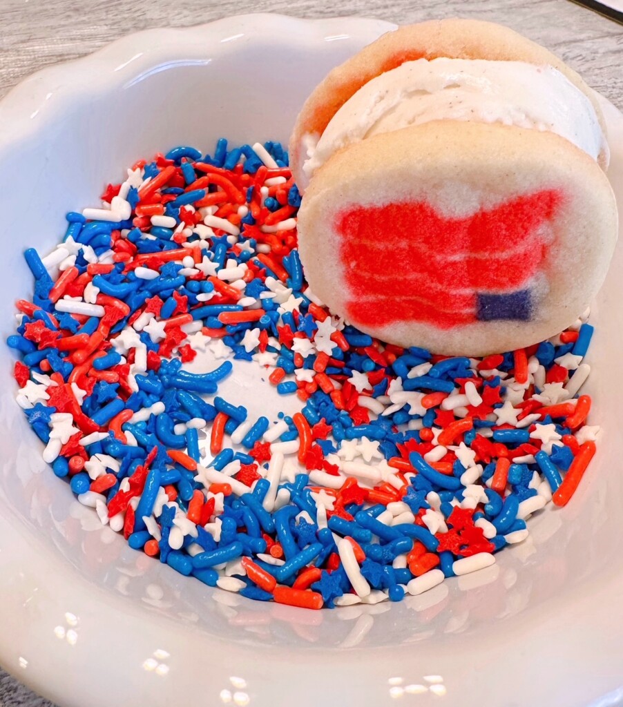 Rolling the sugar cookie ice cream sandwich in the colored sprinkles.