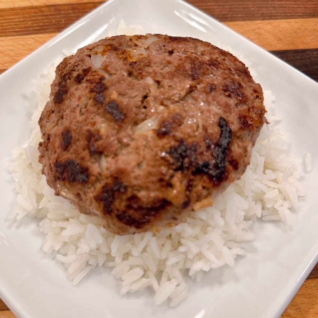 Assembling the Loco Moco. Placing the cooked patty on top of the cooked rice.