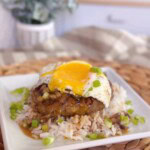 Loco Moco on a serving plate with lots of gravy and a runny egg on top.