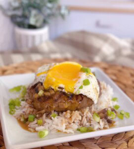 Loco Moco on a serving plate with lots of gravy and a runny egg on top.