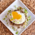 Loco Moco on a white square plate with the yolk running down the sides of the beef patty.