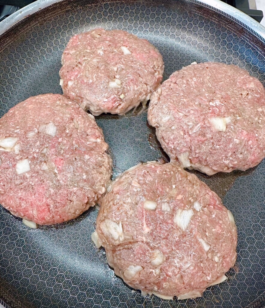 Cooking Patties in a large skillet on the stove top.