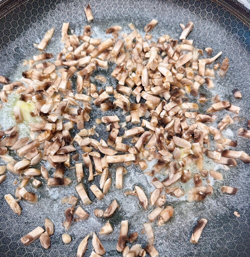 Adding chopped mushrooms to melted butter in a large skillet.