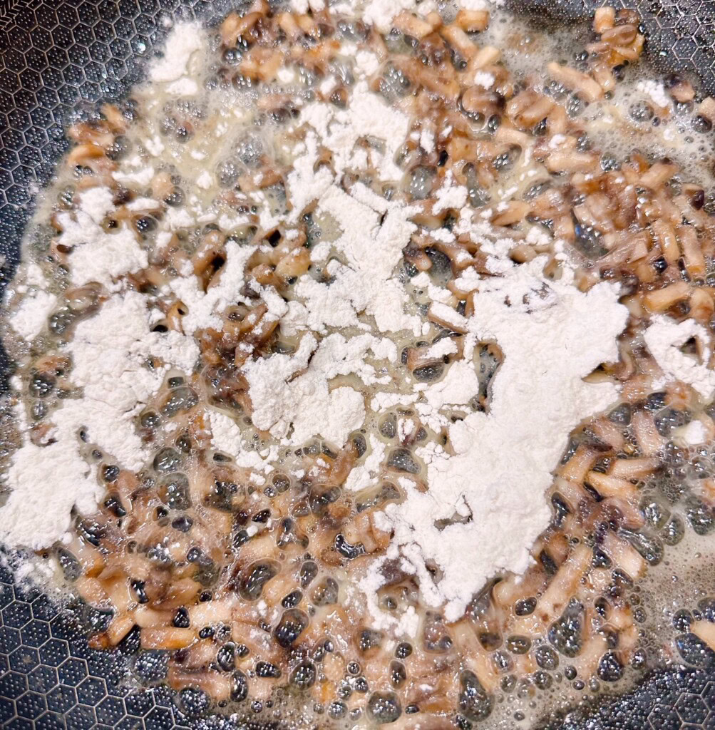 Adding flour to mushrooms and butter.