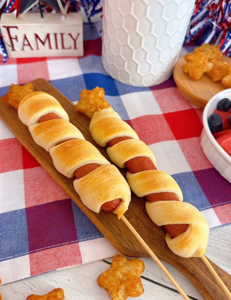 Two Stars and Stripes hot dog skewers on a mini cutting board.