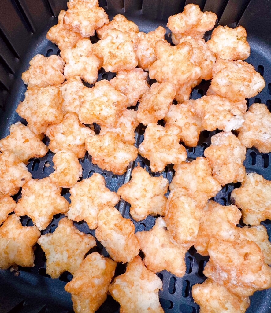Star tater tots in baking basket of air fryer.