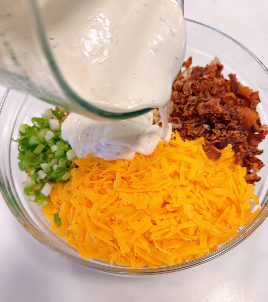 Adding Ranch dressing to pasta salad.