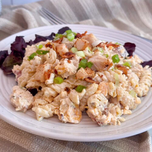 Chicken Bacon Ranch Pasta Salad serving on a plate with red leaf lettuce.